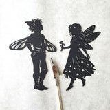 Black paper shadow puppet  cutouts of a fairy and a fairy-like creature on a white background.
