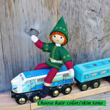 Red haired Kindness elf sitting on a toy train.